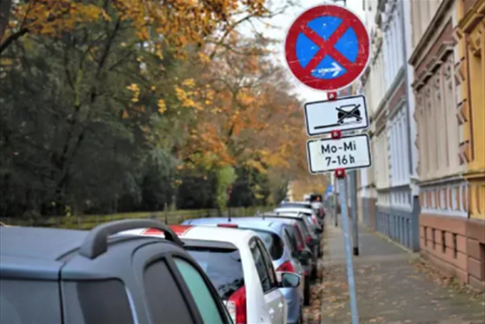 Verkehrszeichen absolutes Halteverbot mit Zusatzschild und Abschlepphinweis an einer Straße mit parkenden Autos