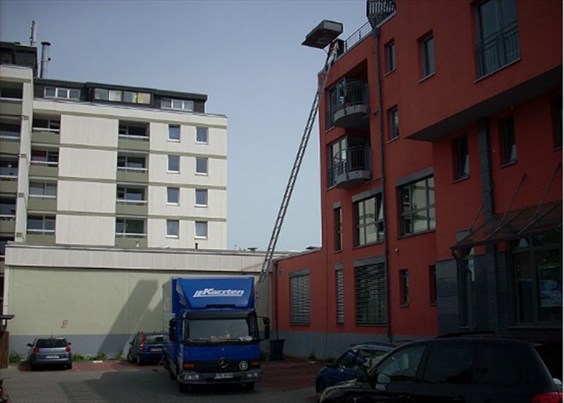 Möbellift der Firma Karsten im Einsatz an einem Mehrfamilienhaus, davor ein blauer Karsten-Möbeltransporter