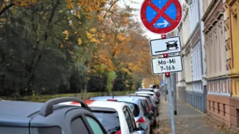 Verkehrszeichen absolutes Halteverbot mit Zusatzschild und Abschlepphinweis an einer Straße mit parkenden Autos